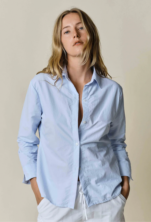 model wearing blue button up shirt on a white background
