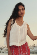model wearing a sleeveless white button down top with ruffles on a boat