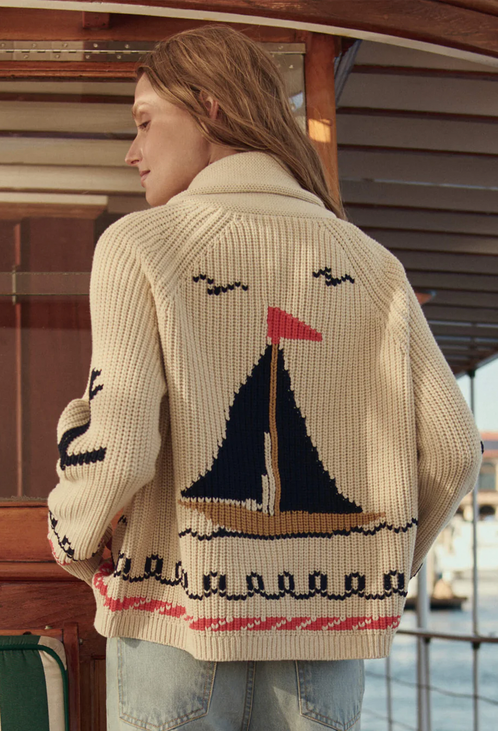 model wearing a beige cardigan with sailboat motifs embroidered 