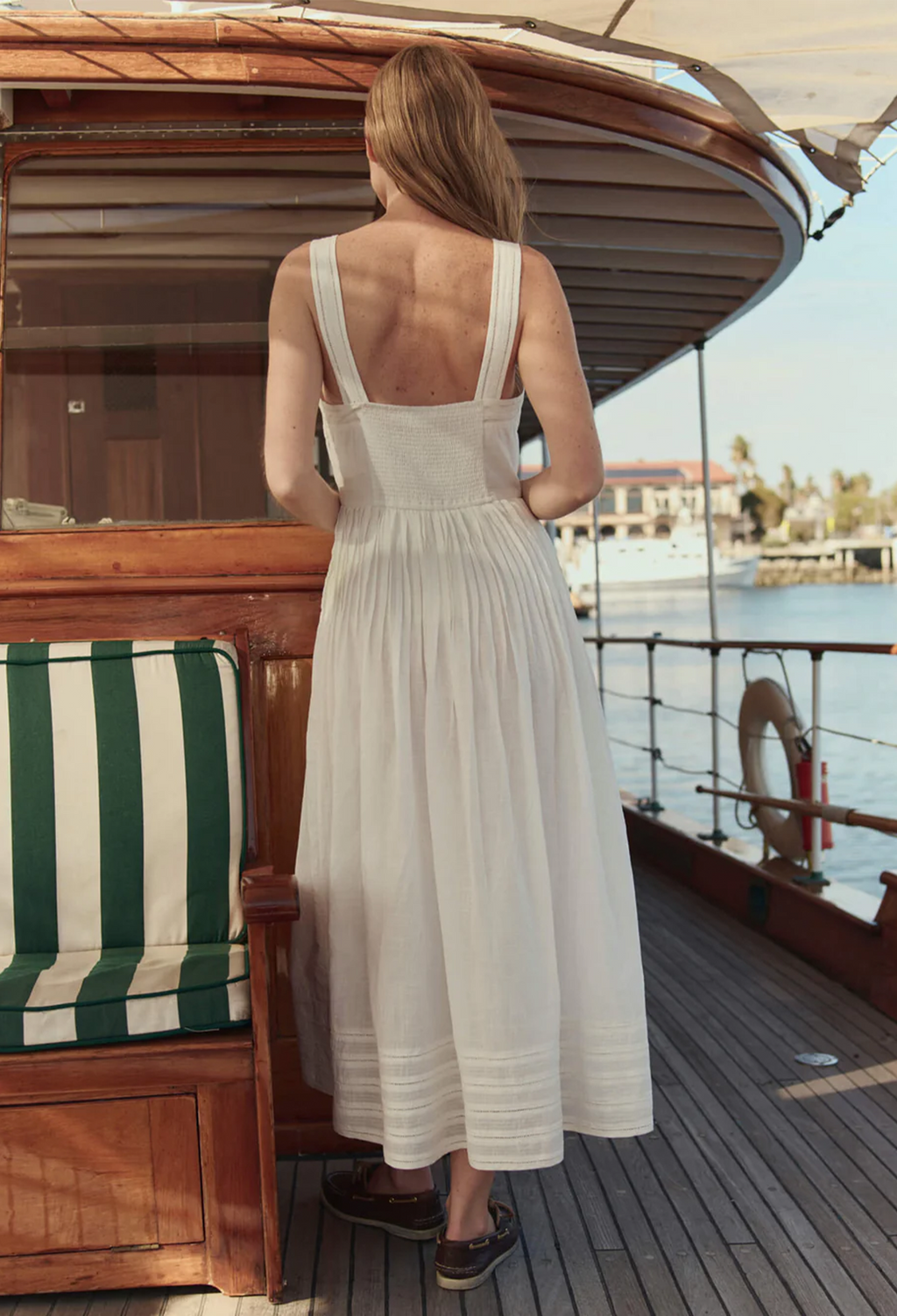 model wearing a sleeveless midi white dress on a boat