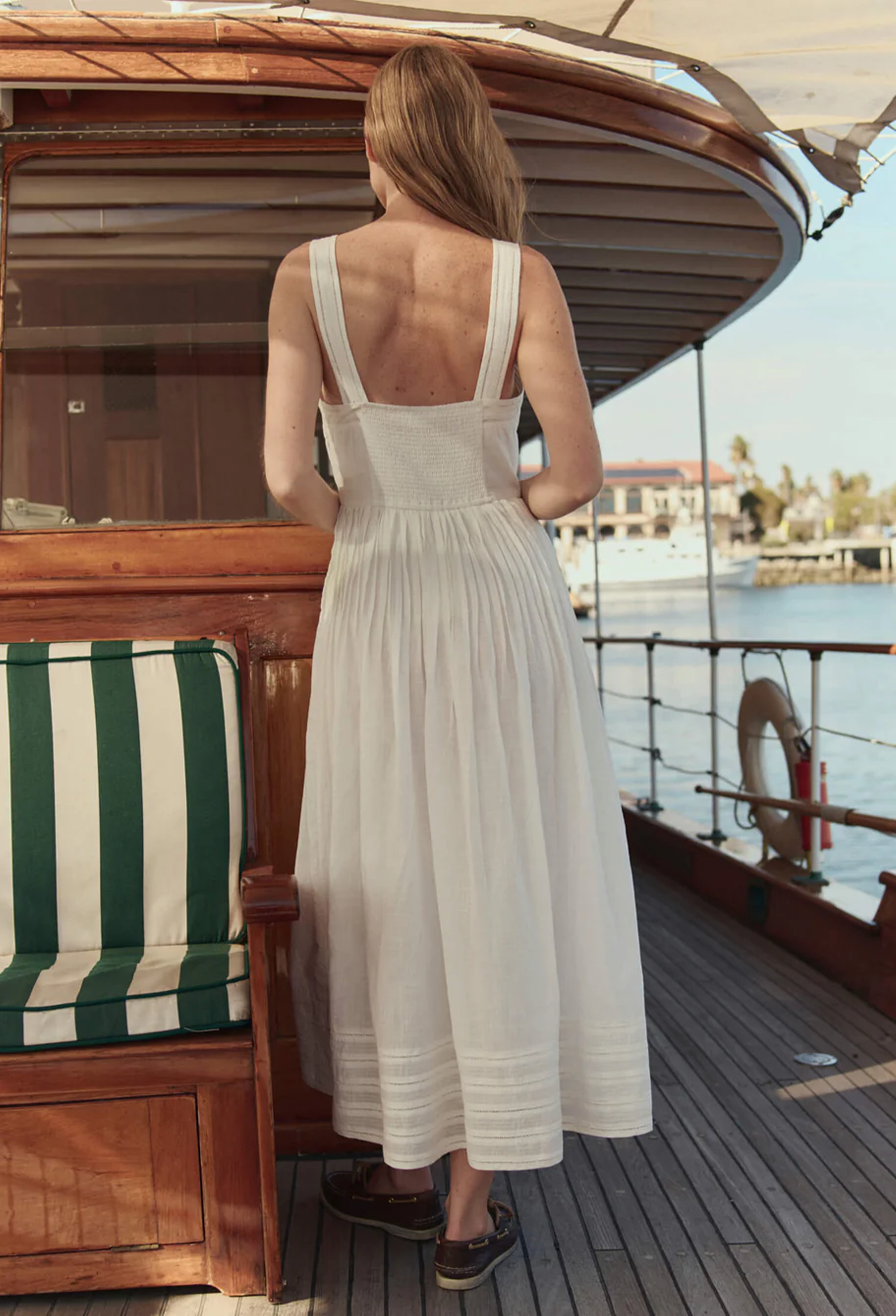 model wearing a sleeveless midi white dress on a boat