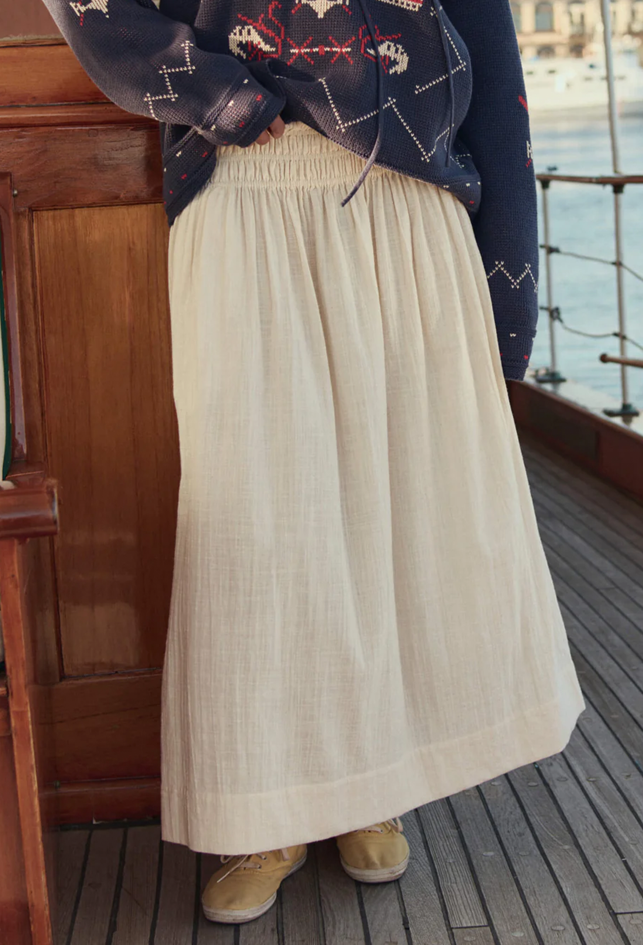 model wearing an off white skirt with a smocked waistband on a boat