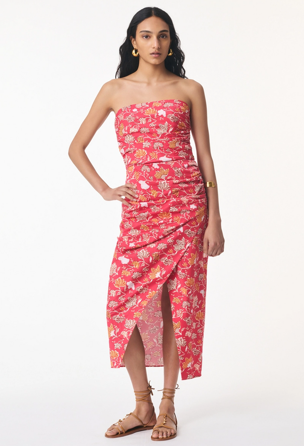 model wearing a floral red strapless dress with a front slit on a white background