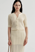 Woman wearing an off white crocheted outfit on a light gray background