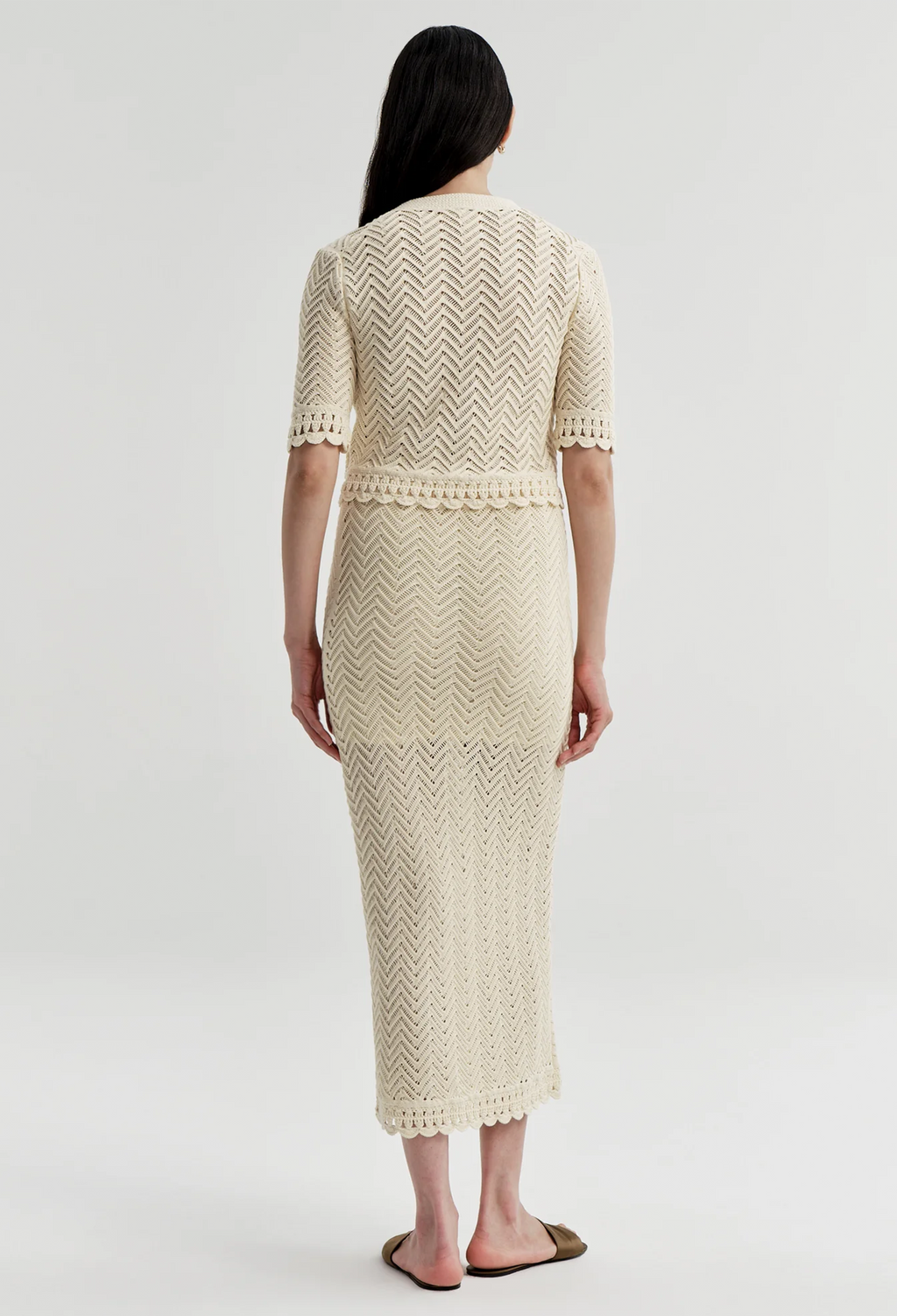 Woman wearing a cream-colored knitted outfit on a white background