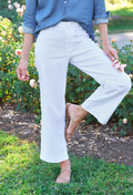 Person wearing white pants and a blue shirt standing in a garden.