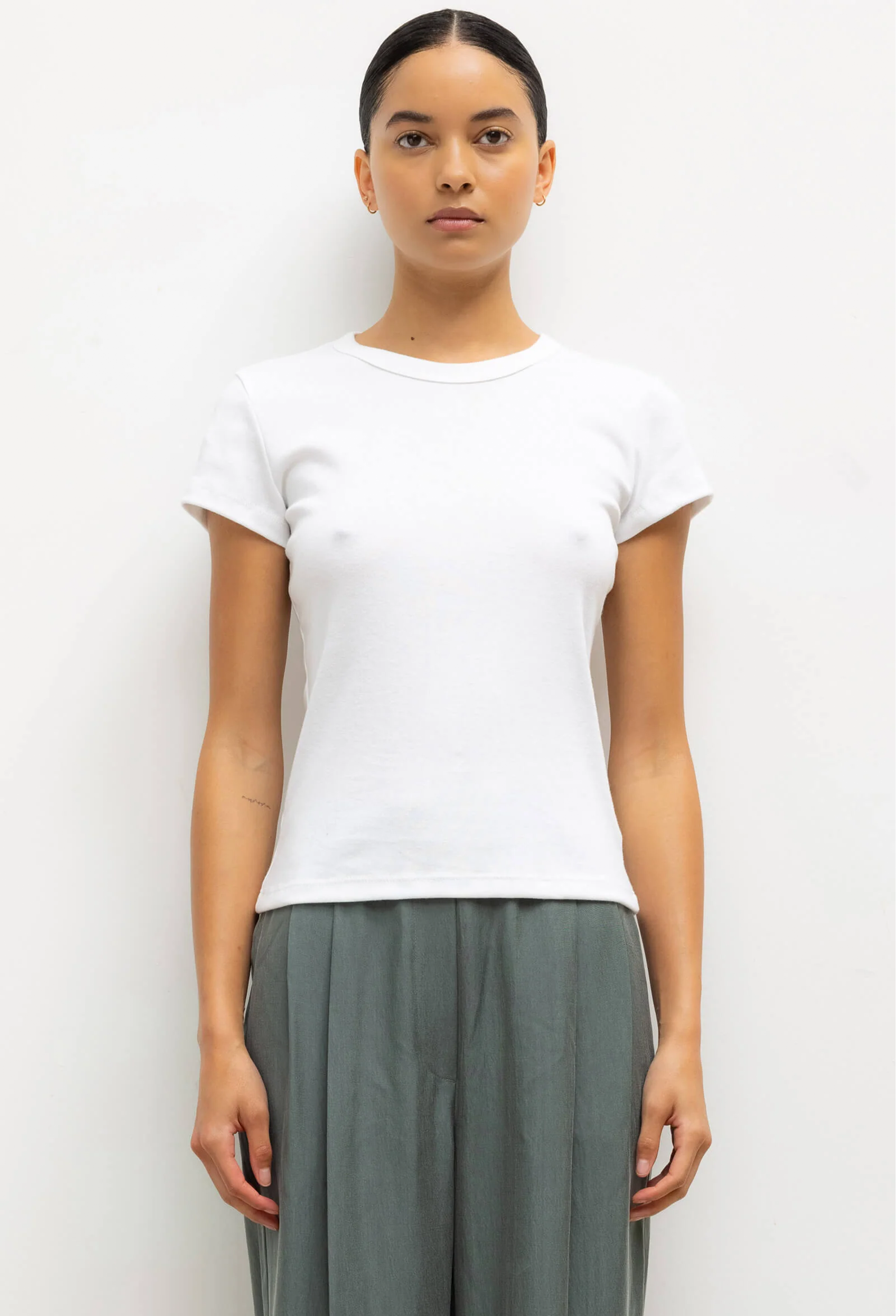 Person wearing a plain white t-shirt and gray pants on a white background