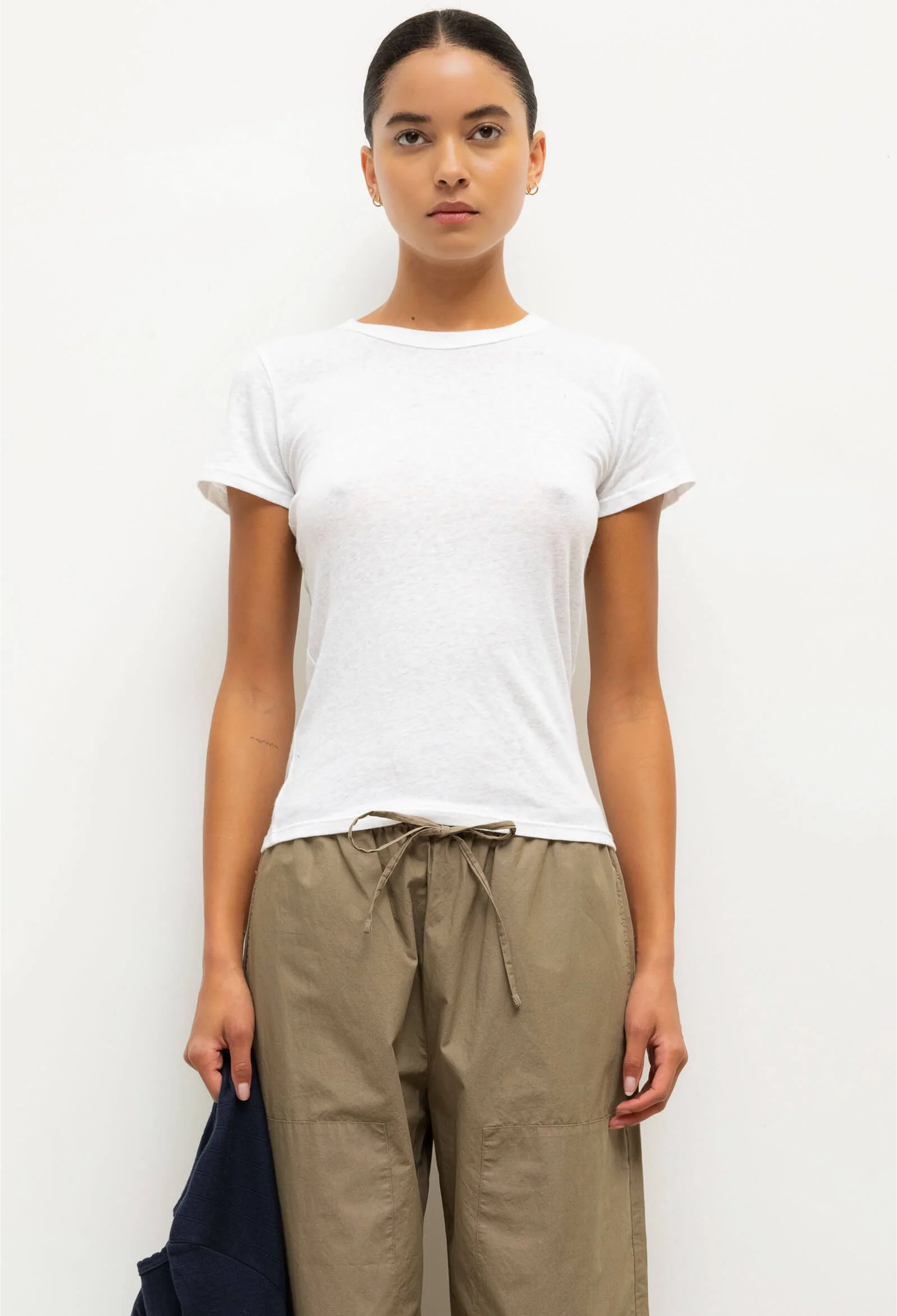 Woman wearing a white t-shirt and beige pants against a white background