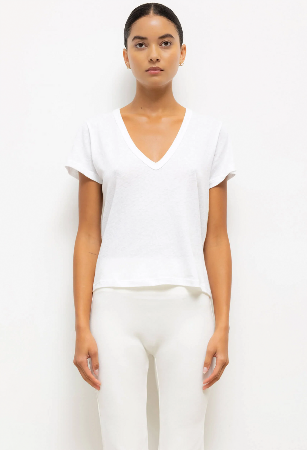 Woman wearing a white V-neck top and pants on a white background