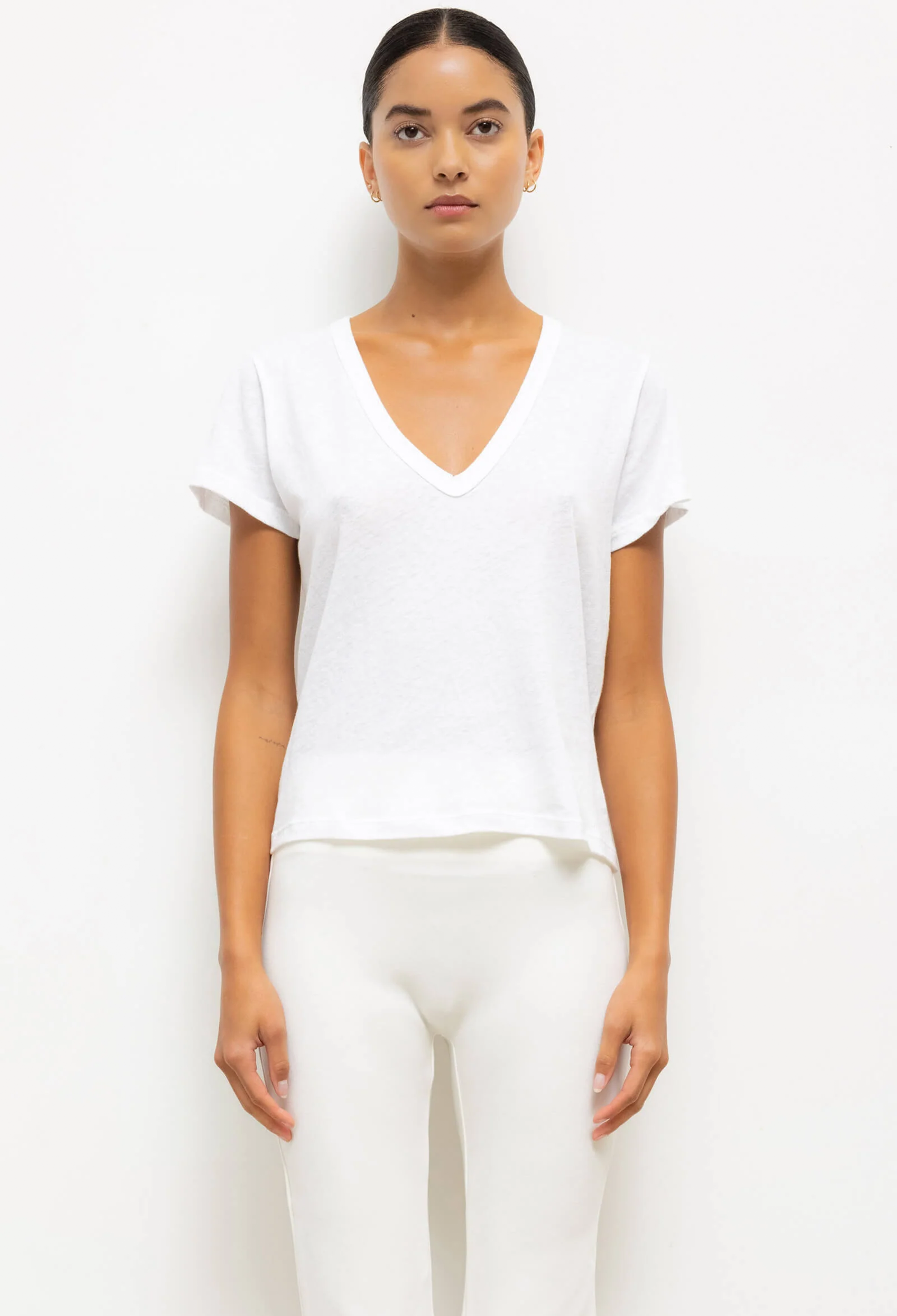 Woman wearing a white V-neck top and pants on a white background