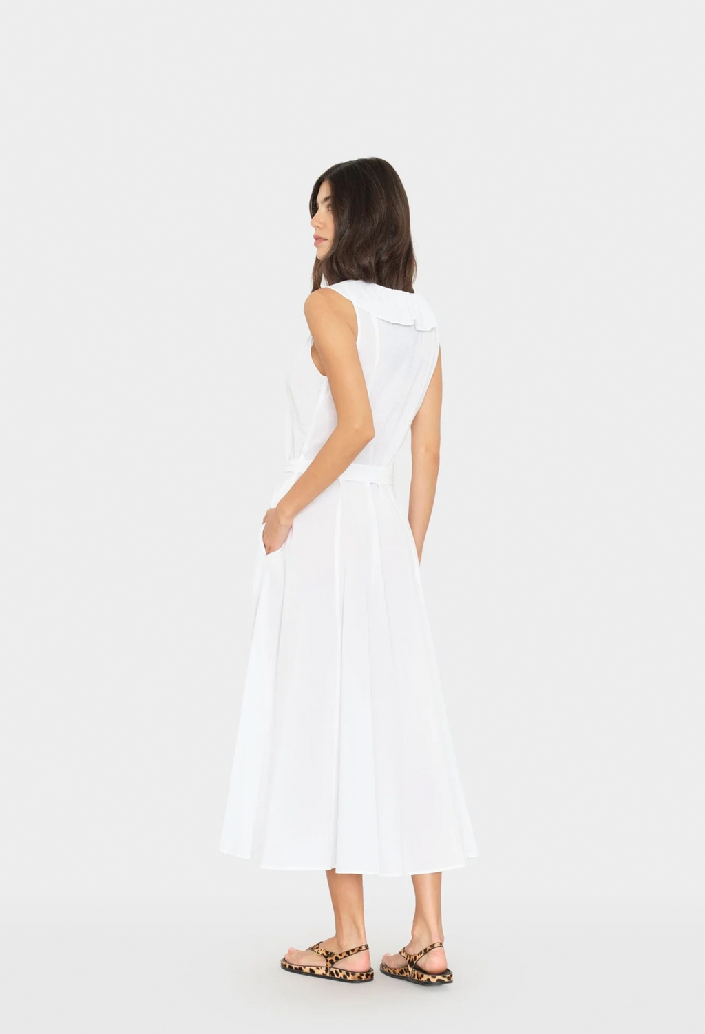 Woman wearing a white sleeveless dress on a plain background
