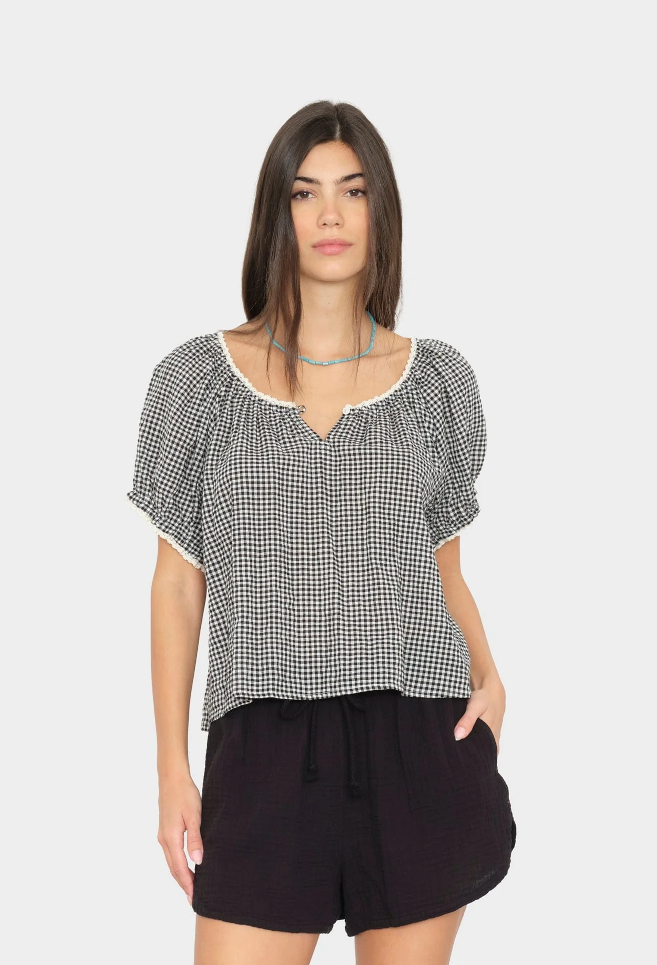 Woman wearing a black and white checkered top with puff sleeves on a white background