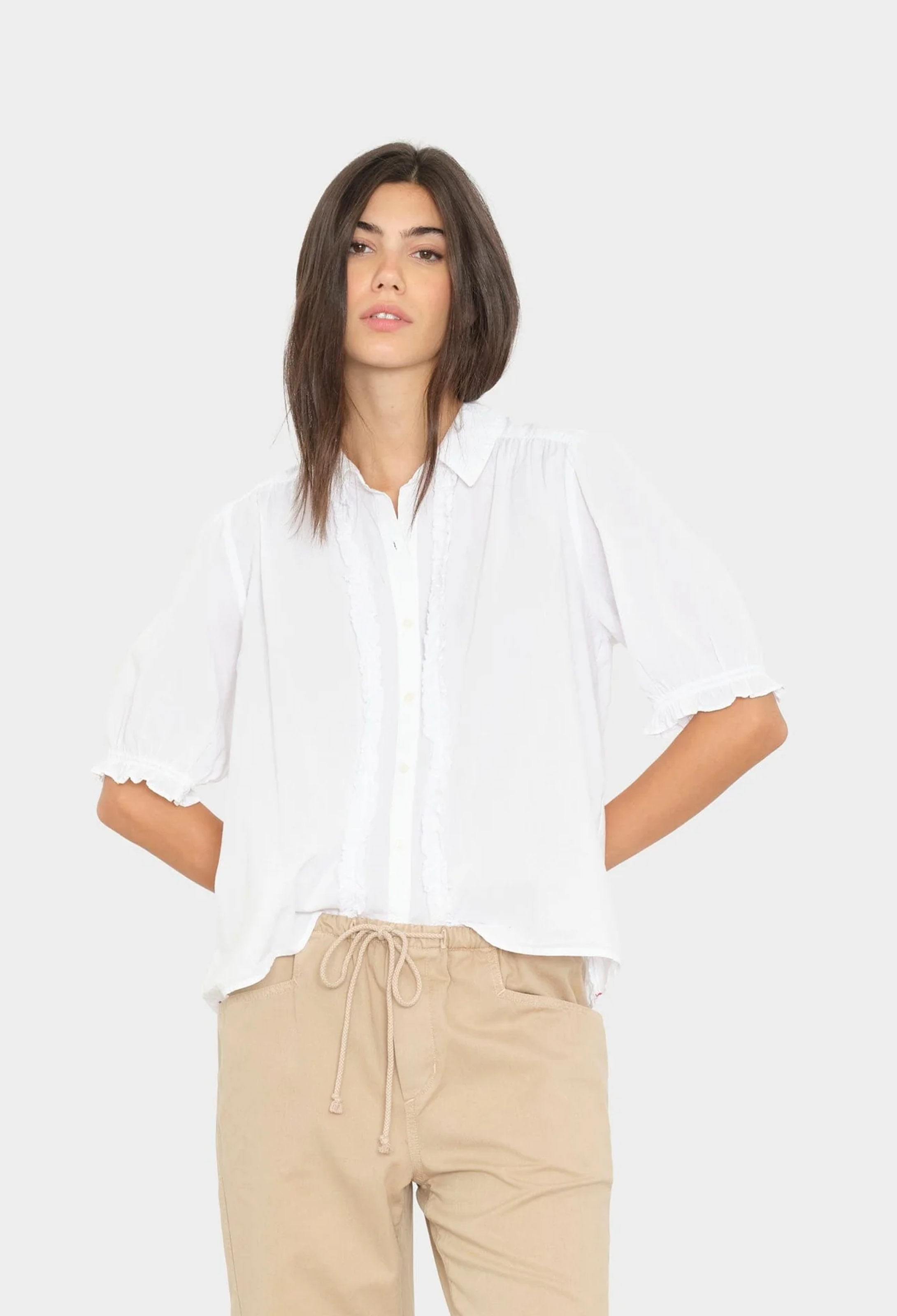 Woman wearing a white shirt and beige pants on a white background