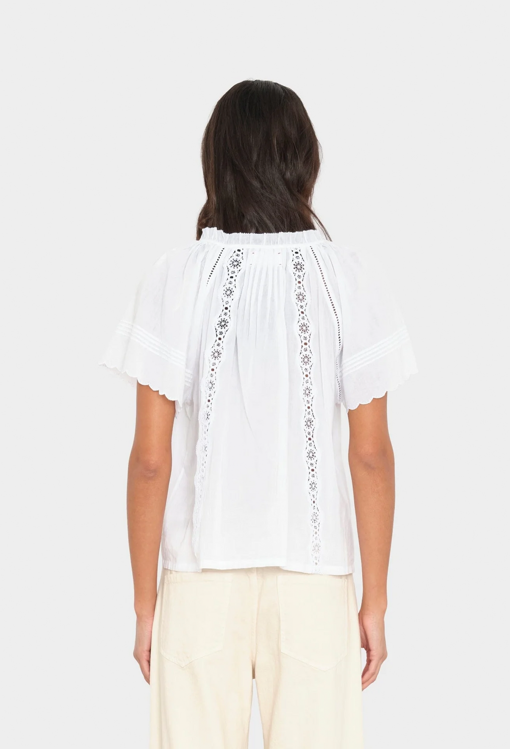 Woman wearing a white blouse with lace details on a white background