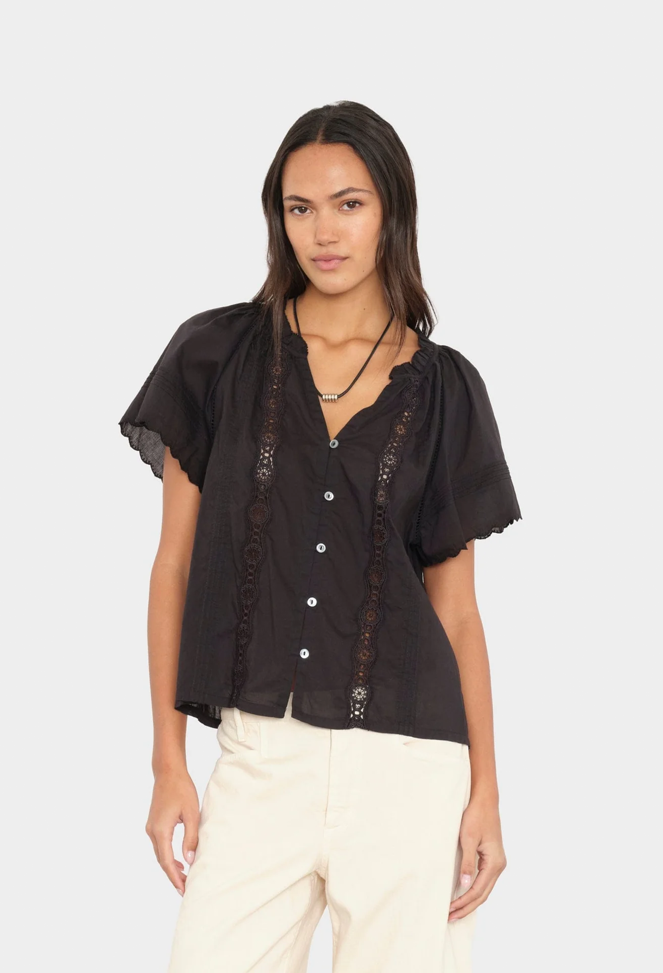 Woman wearing a black blouse with lace details on a white background