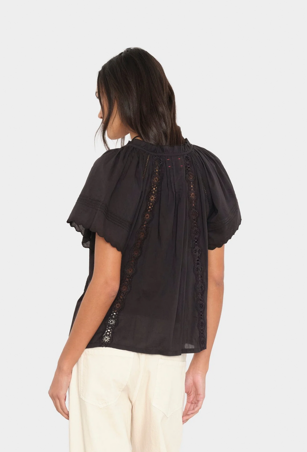 Woman wearing a black blouse with lace details on a white background