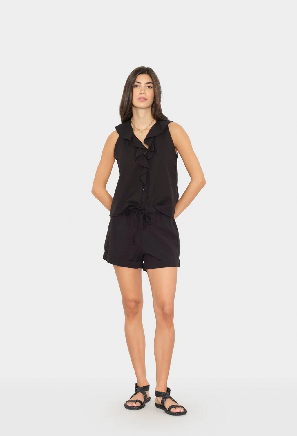 Woman wearing a black sleeveless top and shorts on a white background