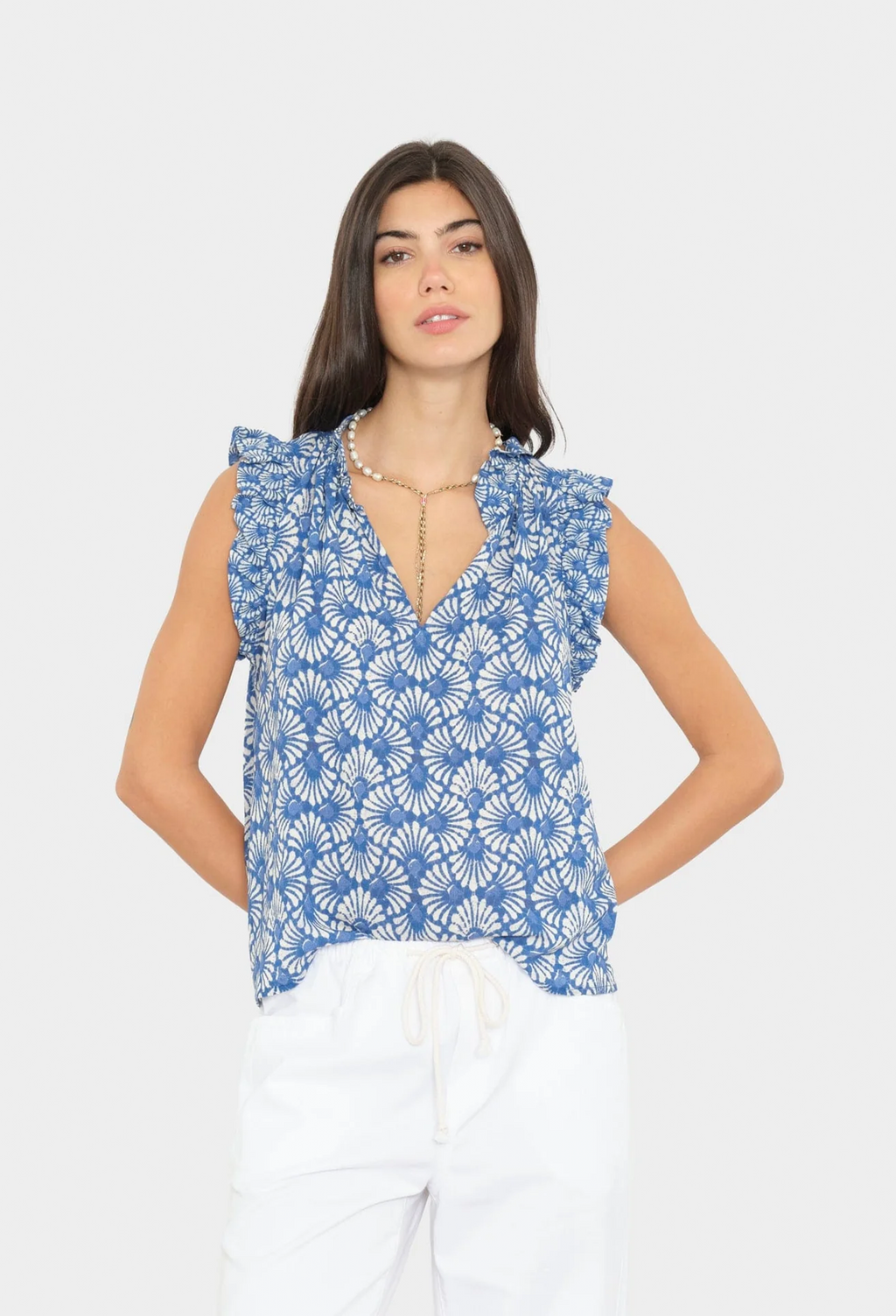 Woman wearing a blue floral sleeveless top against a white background