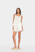 Woman wearing a white lace-trimmed top and shorts set on a white background