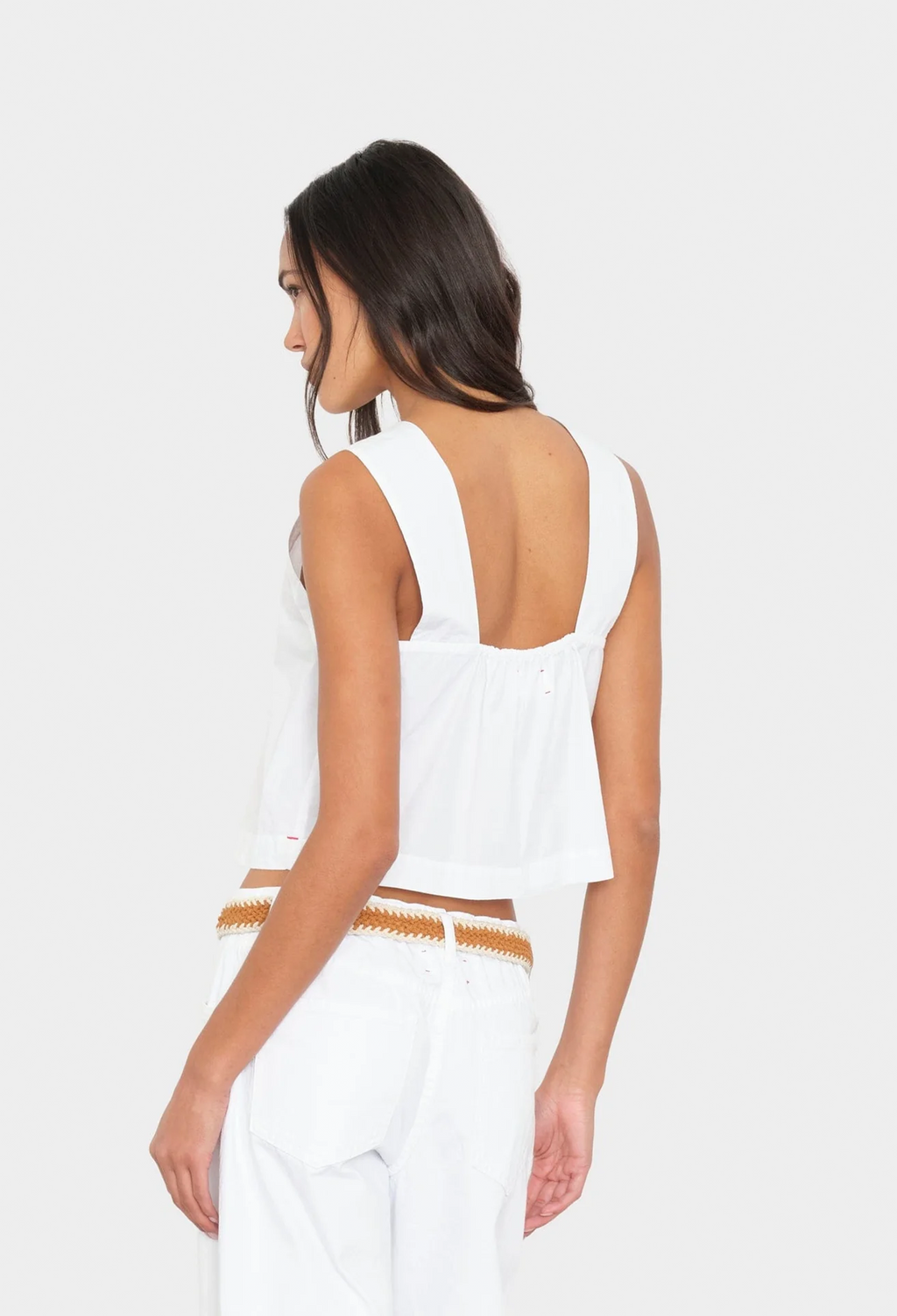 Woman wearing a white sleeveless top with a cutout design on a white background