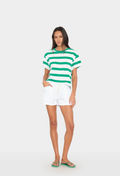 Woman wearing a green and white striped shirt and white shorts on a white background
