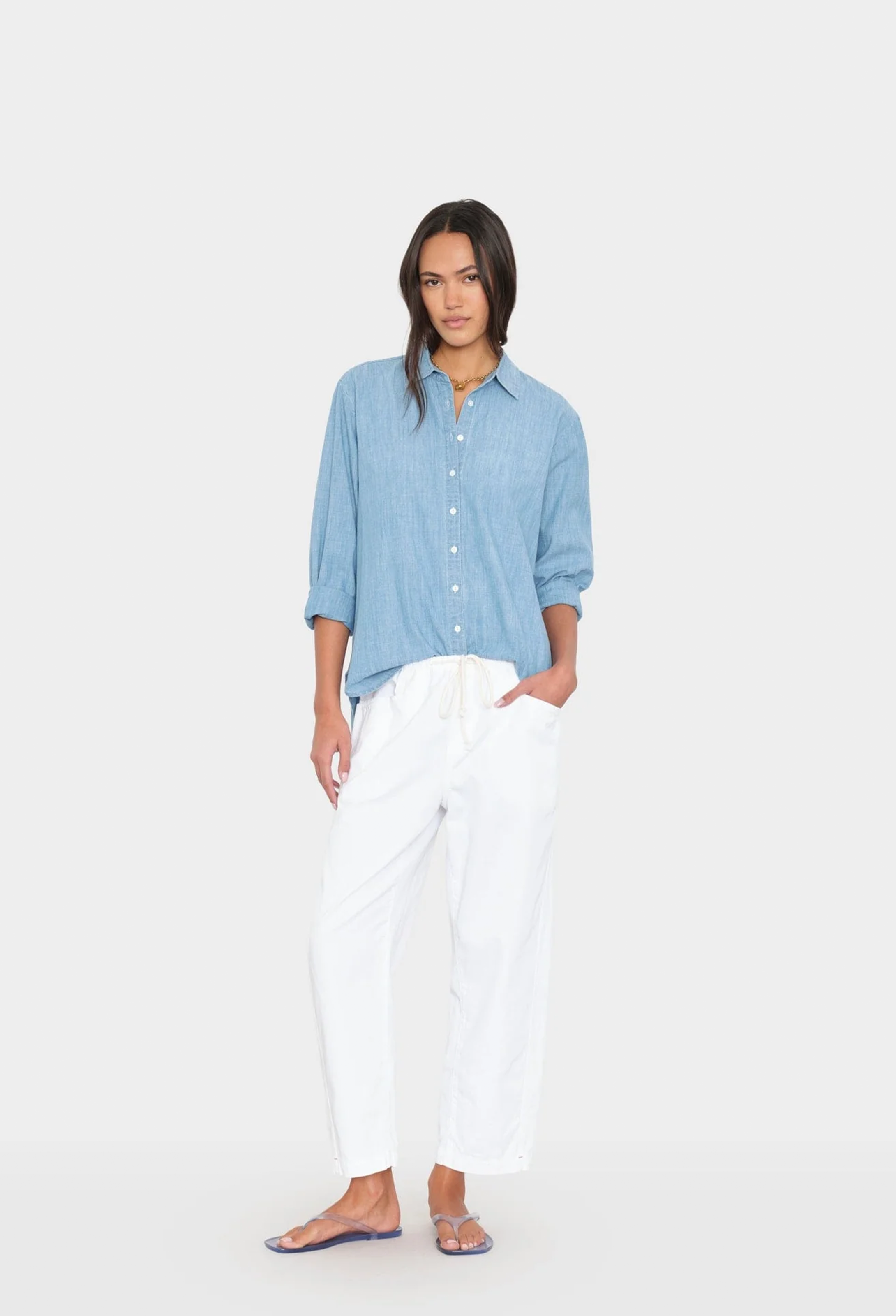 Woman wearing a blue shirt and white pants on a white background