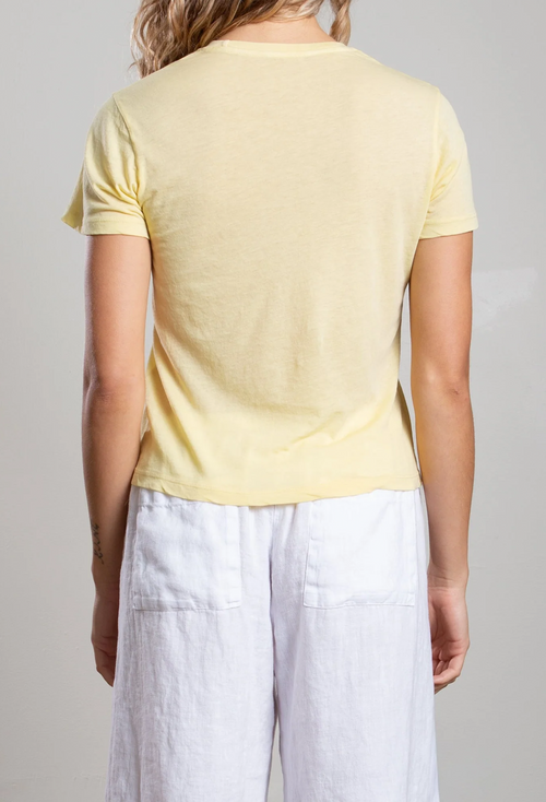 Person wearing a light yellow t-shirt and white pants on a plain background