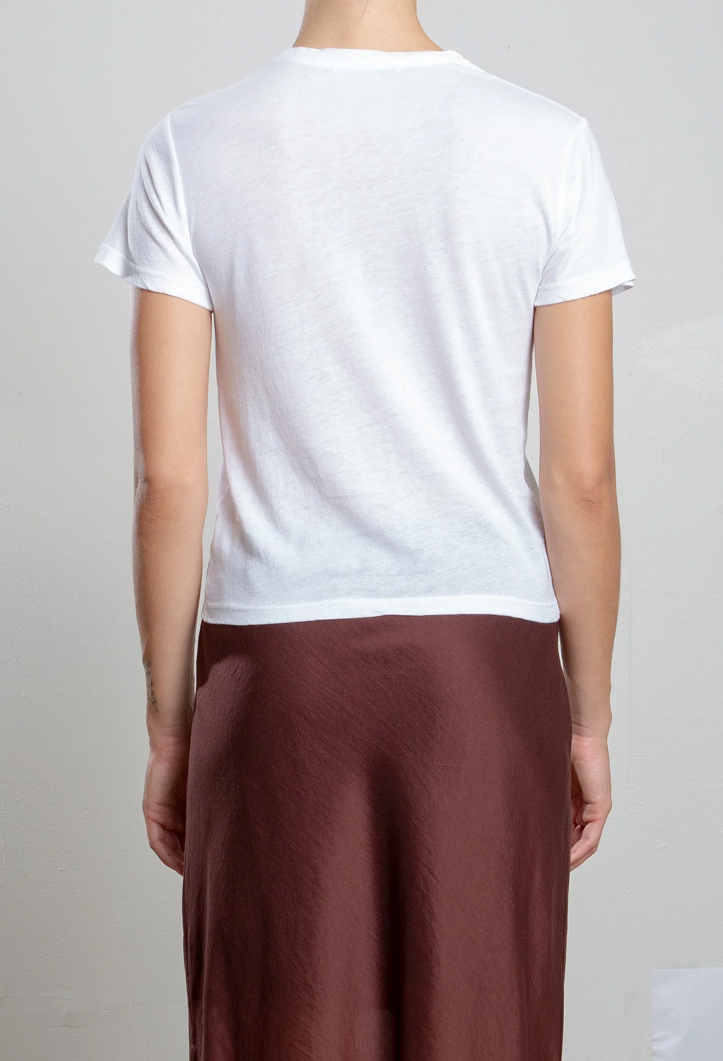Person wearing a white t-shirt and brown pants on a plain background