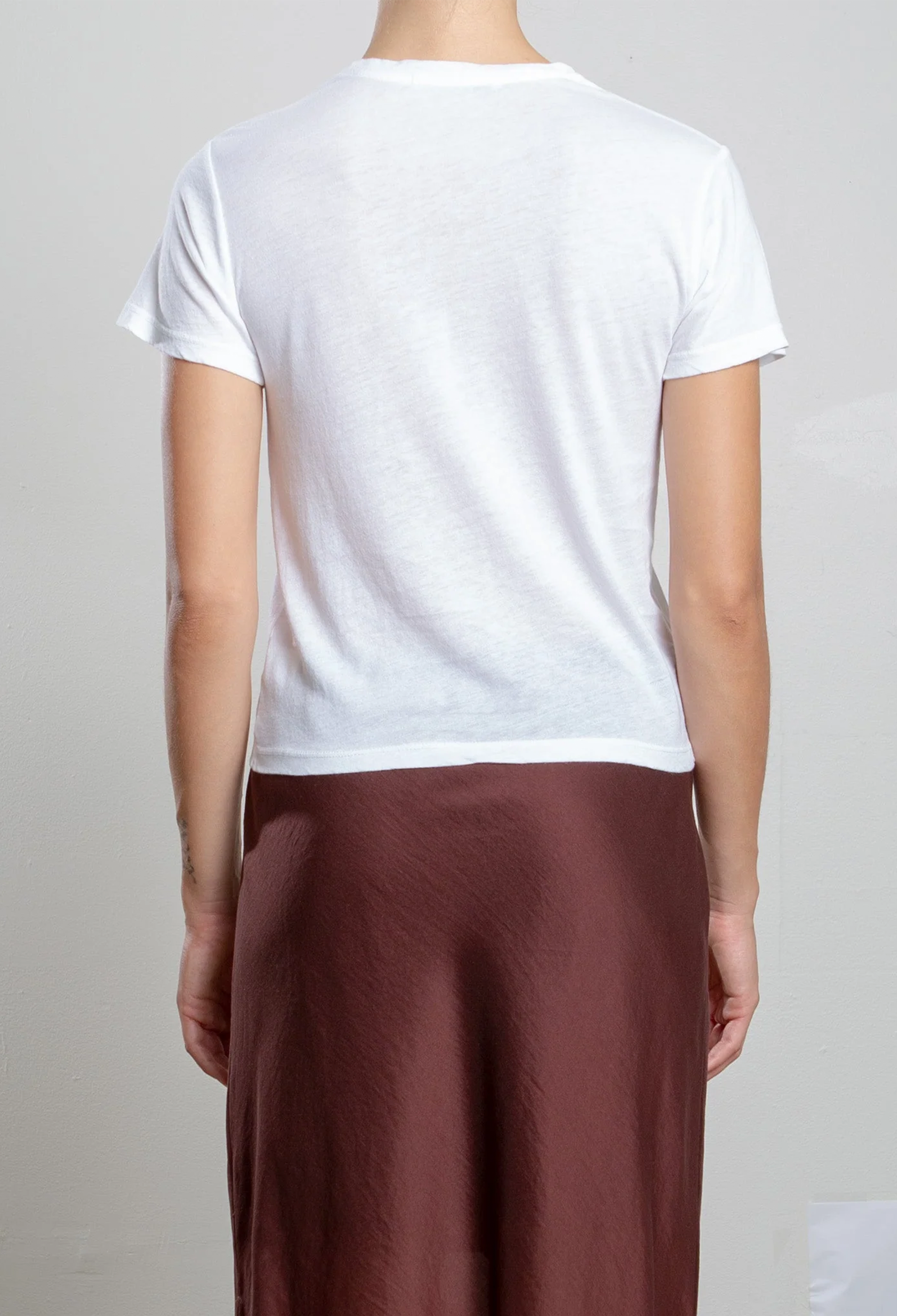 Person wearing a white t-shirt and brown pants on a plain background