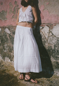 Person wearing a white outfit standing against a textured wall.