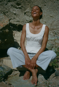 Person wearing a white dress sitting on rocks with a textured wall background