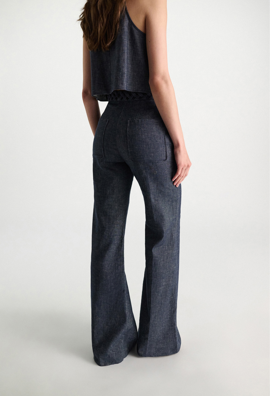 Person wearing dark denim flared pants on a white background