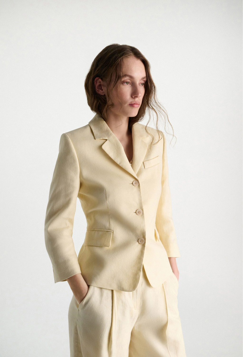 Woman wearing a light yellow suit against a white background