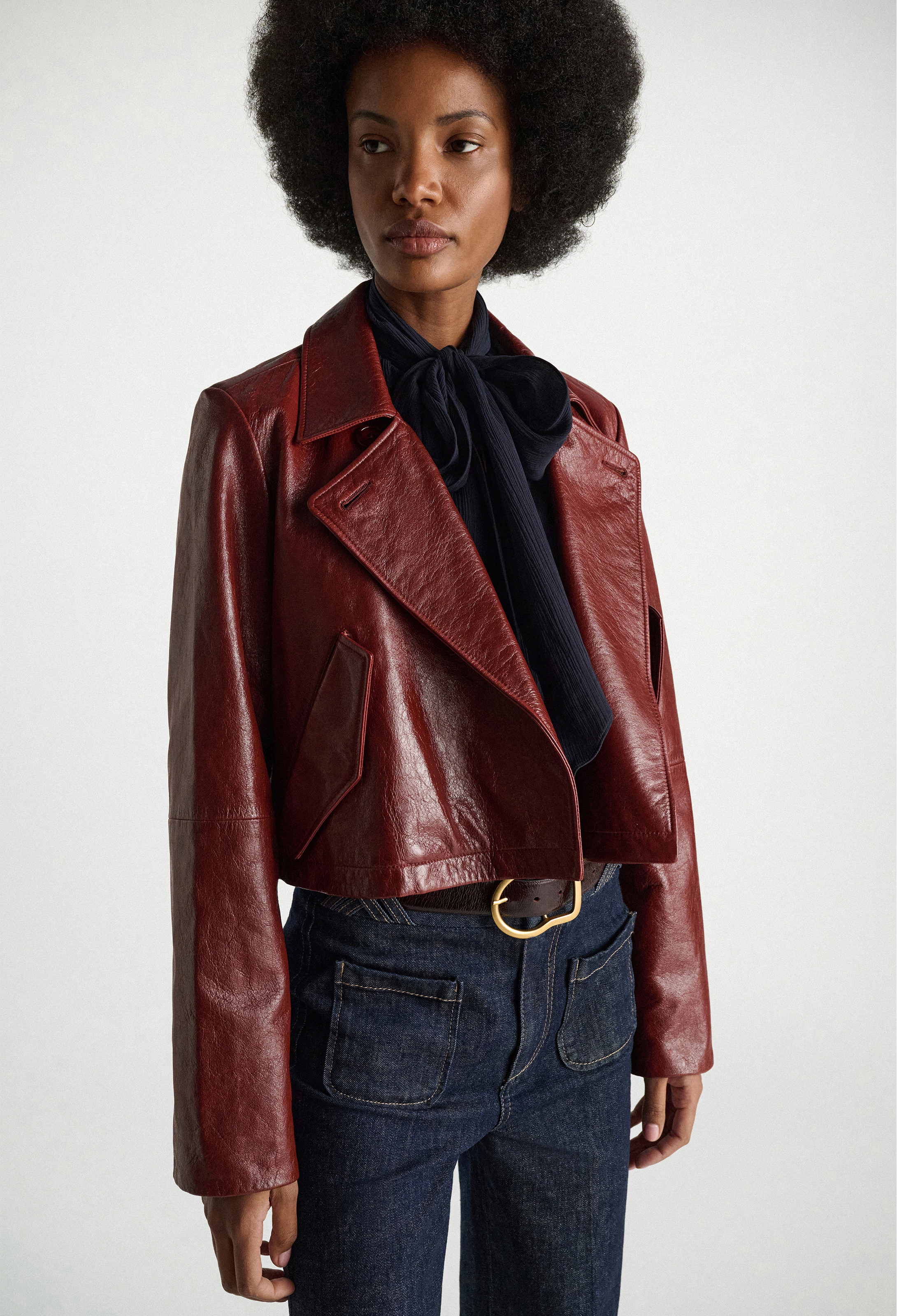 Woman wearing a red leather jacket and blue jeans on a white background