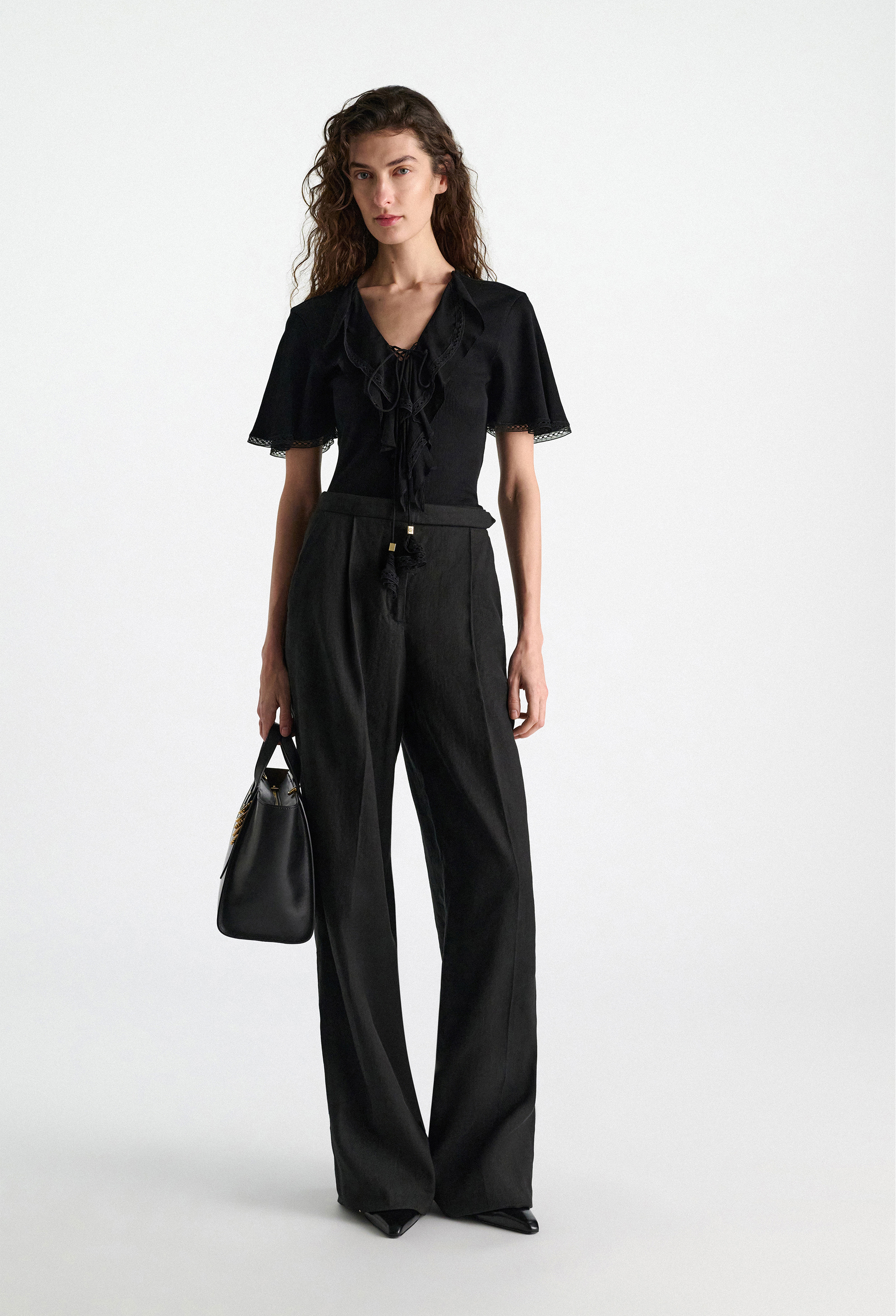 Woman wearing a black outfit with wide-leg pants on a white background