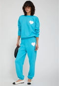 Person wearing a turquoise sweat suit with white hearts on a plain background
