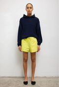 Person wearing a navy hoodie and yellow shorts against a white background