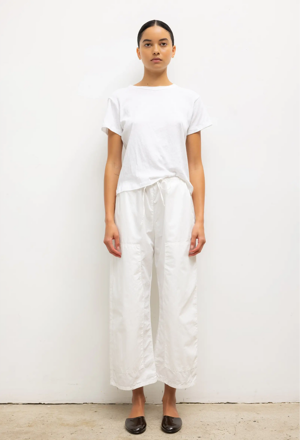 Person wearing a white t-shirt and wide-leg pants against a plain background