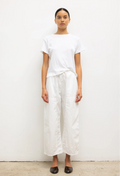 Person wearing a white t-shirt and wide-leg pants against a plain background