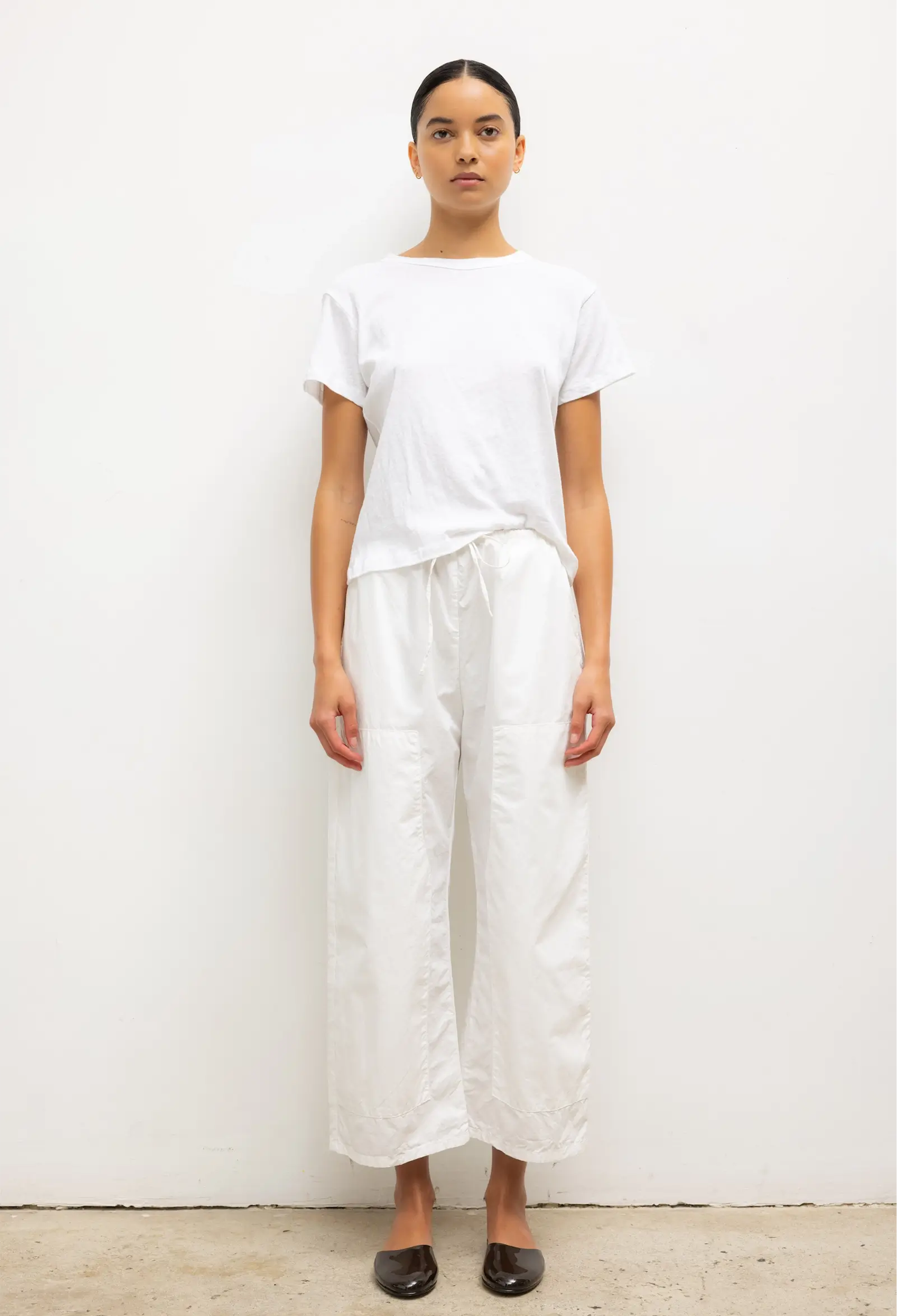 Person wearing a white t-shirt and wide-leg pants against a plain background