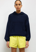 Person wearing a navy blue hoodie and yellow shorts on a white background