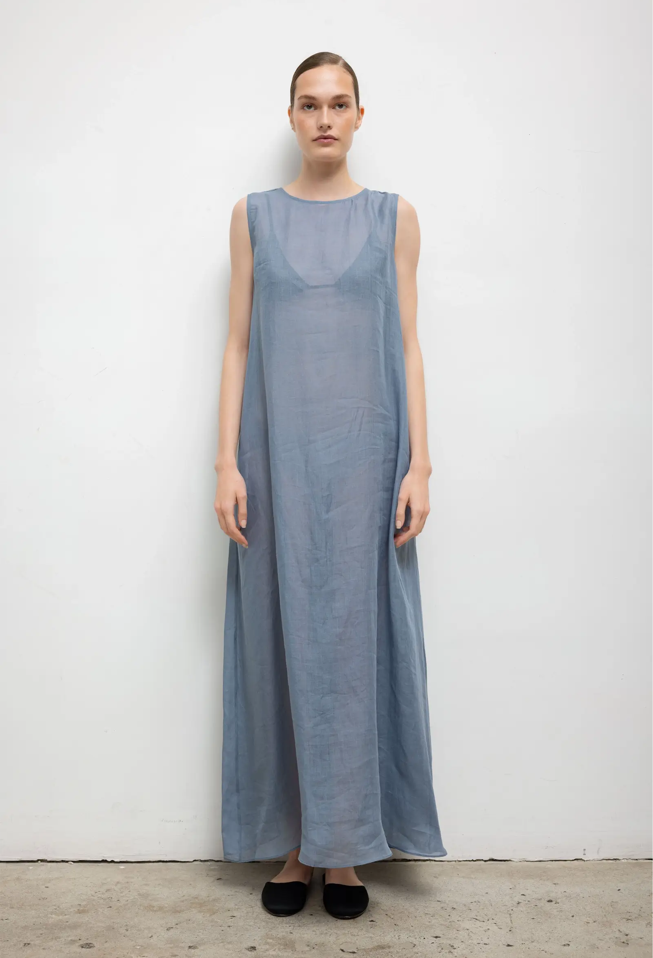 Woman wearing a long light blue dress against a white background