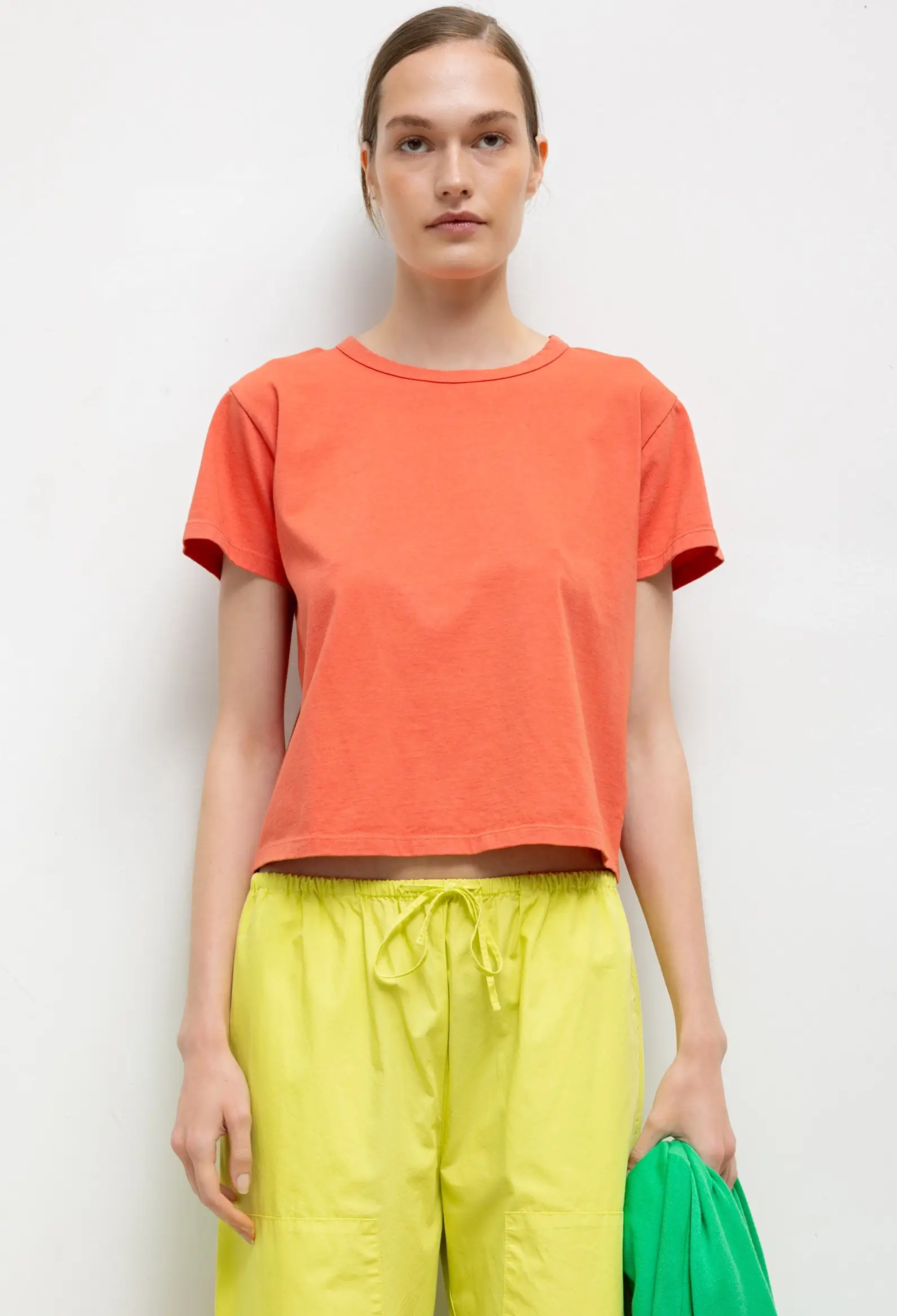 Person wearing an orange t-shirt and yellow pants against a white background