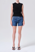 Person wearing a black sleeveless top and blue denim shorts on a white background
