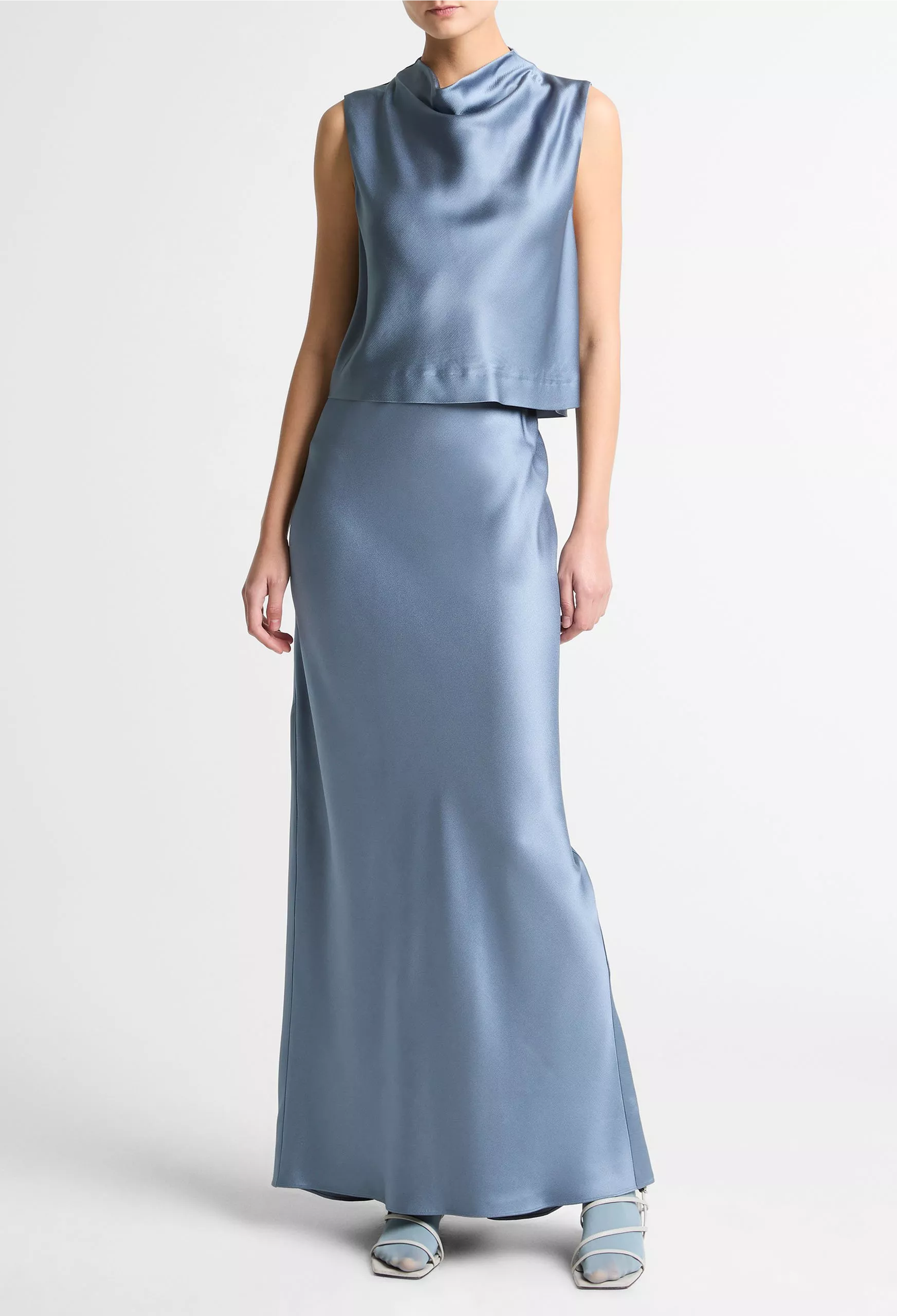 Woman wearing a light blue sleeveless top and long skirt set on a white background