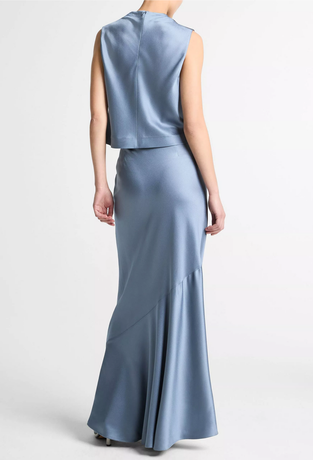 Woman wearing a light blue sleeveless top and long skirt set on a white background
