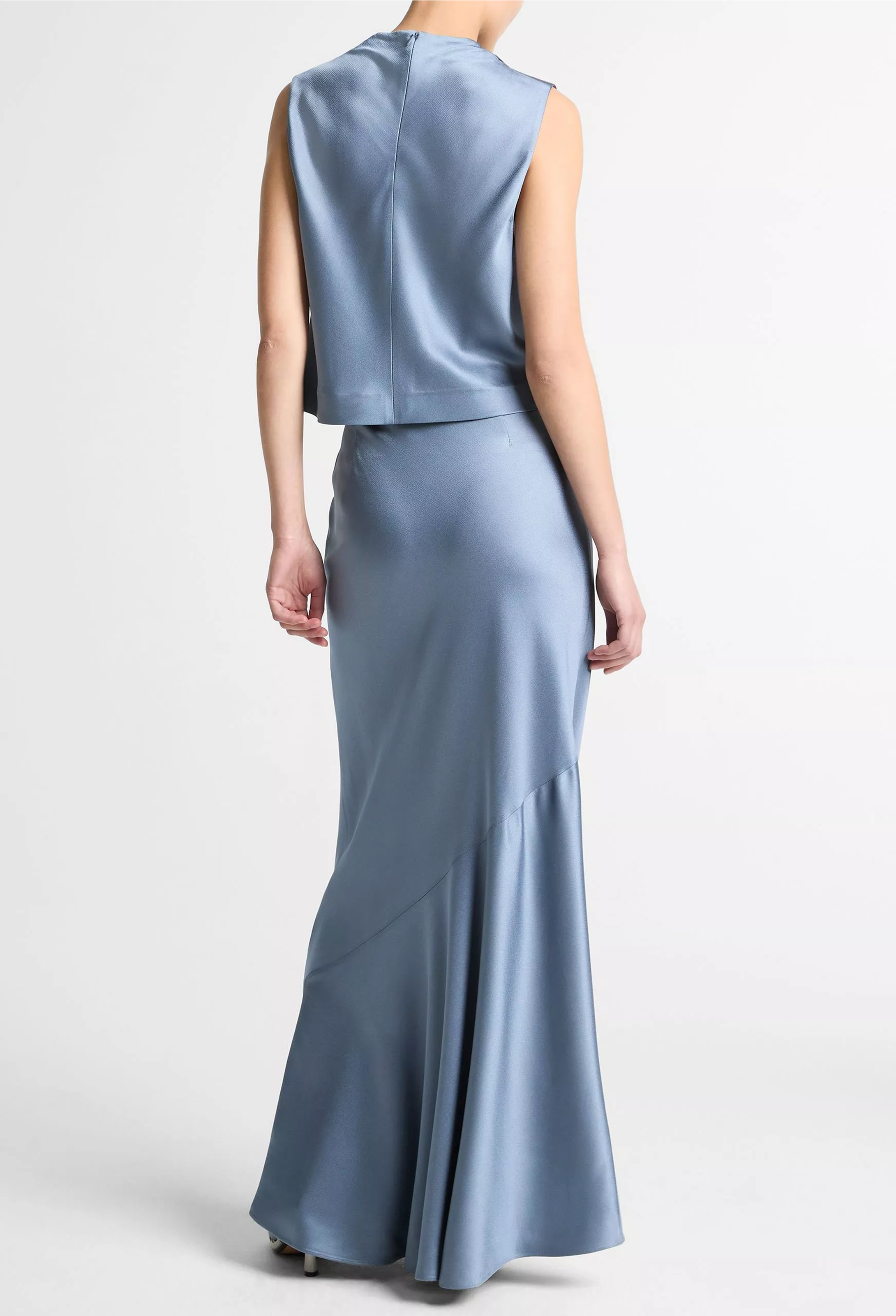 Woman wearing a light blue sleeveless top and long skirt set on a white background