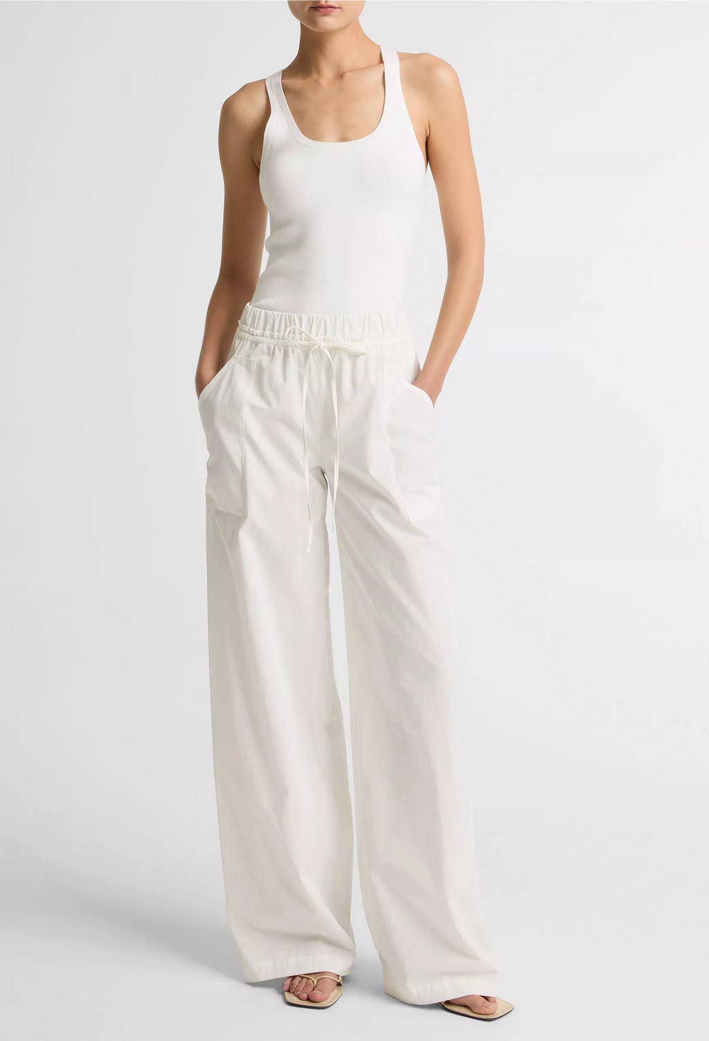 Person wearing a white tank top and wide-leg pants on a light gray background