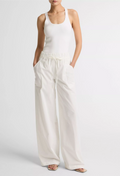 Person wearing a white tank top and wide-leg pants on a light gray background