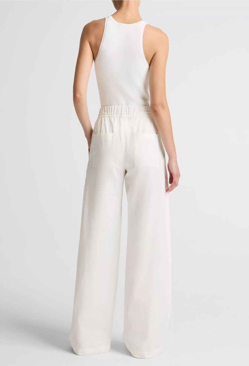 Person wearing a white sleeveless top and wide-leg pants on a light gray background